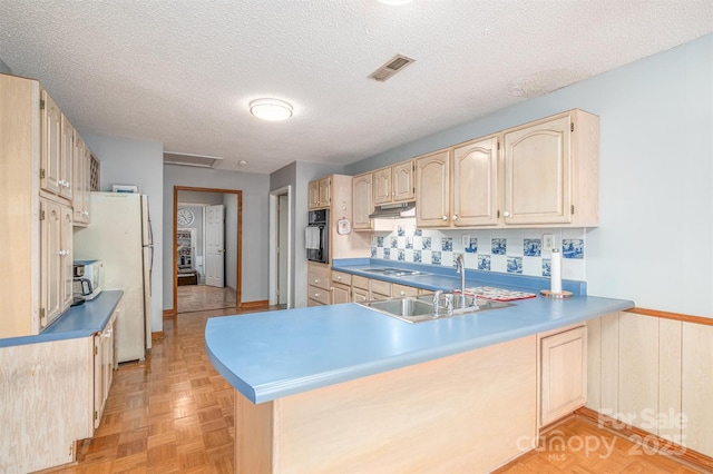 kitchen with visible vents, a peninsula, light countertops, a sink, and black oven