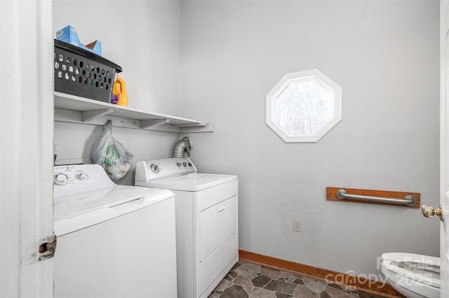 washroom with stone finish floor, laundry area, baseboards, and separate washer and dryer