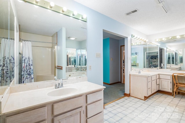 bathroom with a textured ceiling, visible vents, two vanities, and a sink