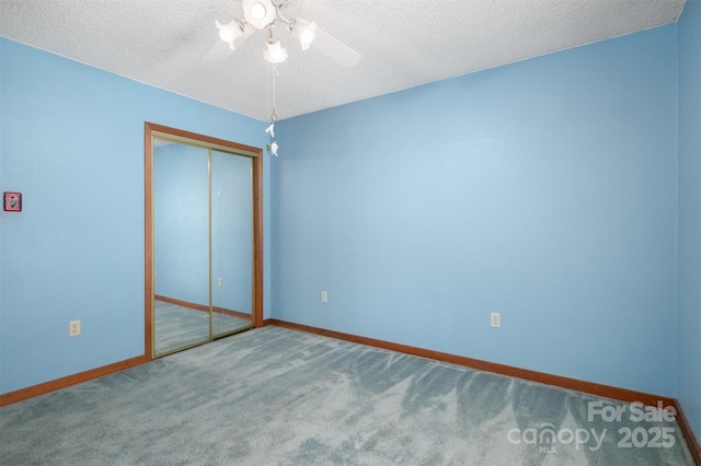 carpeted spare room with a ceiling fan, a textured ceiling, and baseboards