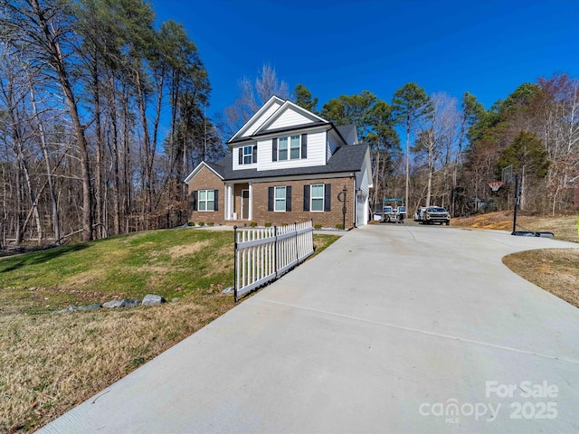 view of front of house featuring concrete driveway, brick siding, a front yard, and fence