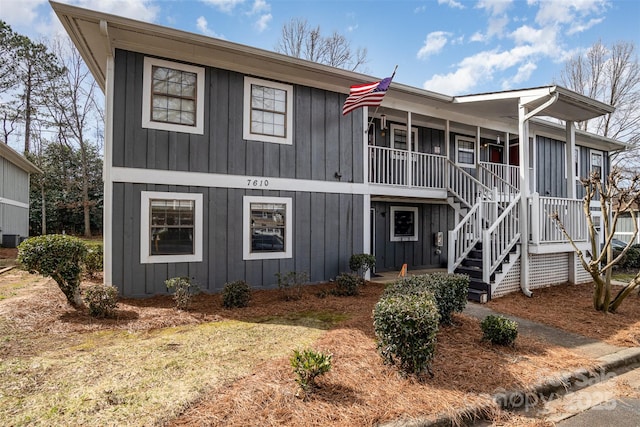 view of front facade with board and batten siding, a porch, and stairway