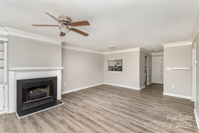 unfurnished living room featuring ornamental molding, a fireplace with raised hearth, baseboards, and wood finished floors