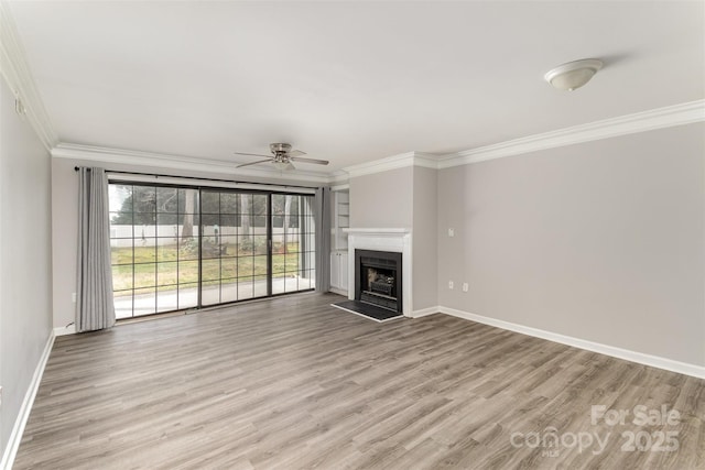 unfurnished living room with light wood-style flooring, a fireplace, a ceiling fan, baseboards, and crown molding