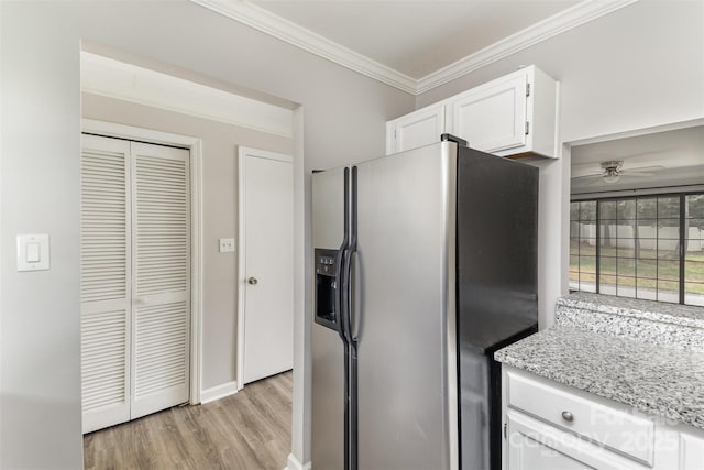 kitchen with stainless steel fridge, white cabinets, light wood-style flooring, light stone countertops, and crown molding