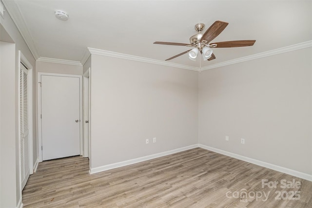 unfurnished room with light wood-style floors, a ceiling fan, baseboards, and crown molding