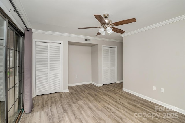 unfurnished bedroom with visible vents, baseboards, crown molding, light wood-type flooring, and two closets