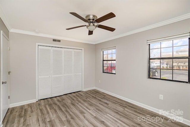 unfurnished bedroom with ornamental molding, light wood-style floors, visible vents, and baseboards