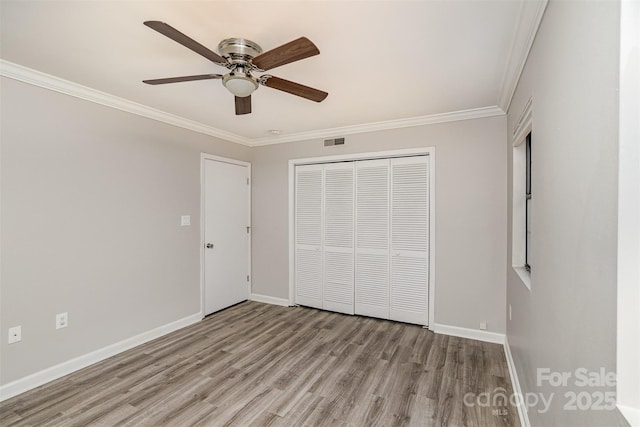 unfurnished bedroom with light wood-style floors, a closet, visible vents, and crown molding