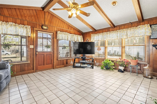 tiled living room with wood walls, plenty of natural light, and lofted ceiling with beams