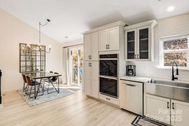 kitchen featuring lofted ceiling, dobule oven black, light wood-style flooring, a sink, and dishwasher