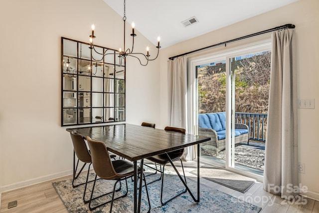 dining area with visible vents, vaulted ceiling, wood finished floors, a chandelier, and baseboards