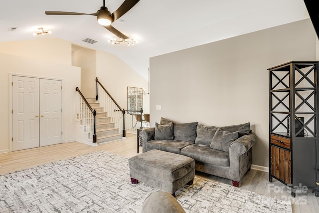 living area featuring light wood-type flooring, stairs, visible vents, and vaulted ceiling