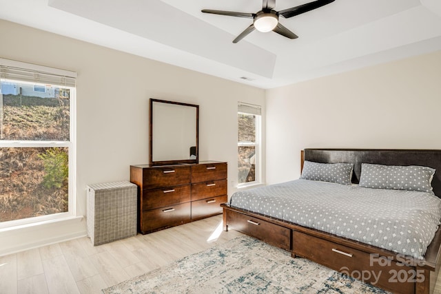 bedroom with visible vents, a raised ceiling, and wood finished floors