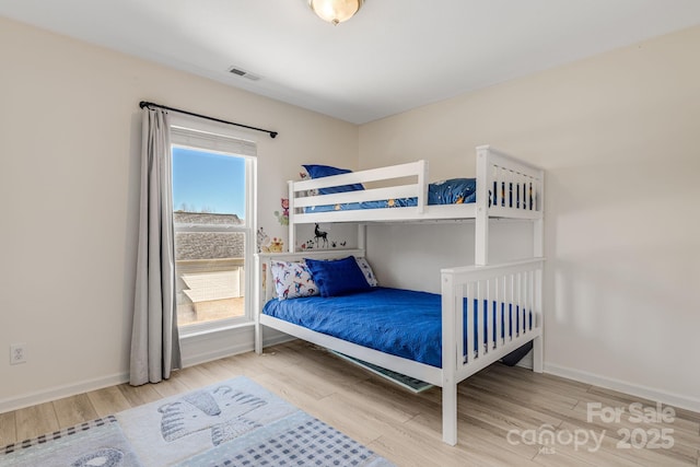 bedroom featuring wood finished floors, visible vents, and baseboards