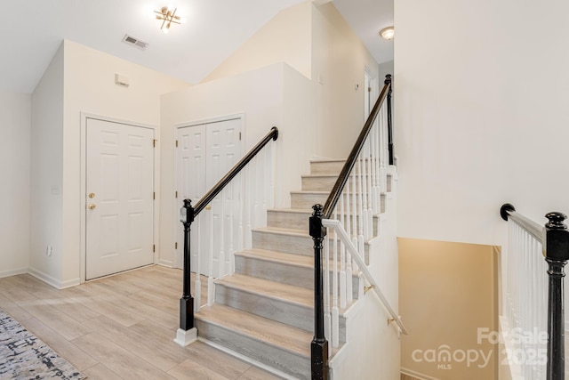 interior space with visible vents, vaulted ceiling, baseboards, and wood finished floors