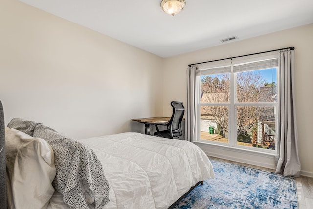 bedroom with baseboards, visible vents, and wood finished floors