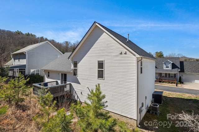 rear view of property featuring a shingled roof and central air condition unit