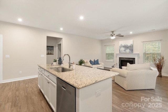 kitchen with a sink, white cabinetry, open floor plan, dishwasher, and a center island with sink