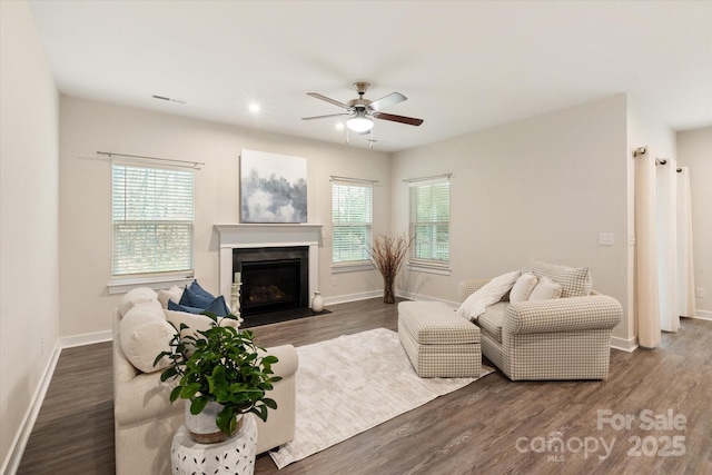 living room featuring a fireplace with flush hearth, plenty of natural light, and dark wood finished floors