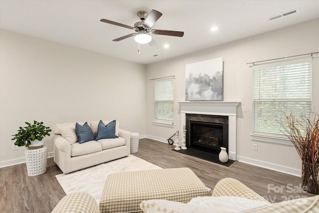 living area with wood finished floors, plenty of natural light, a glass covered fireplace, and visible vents