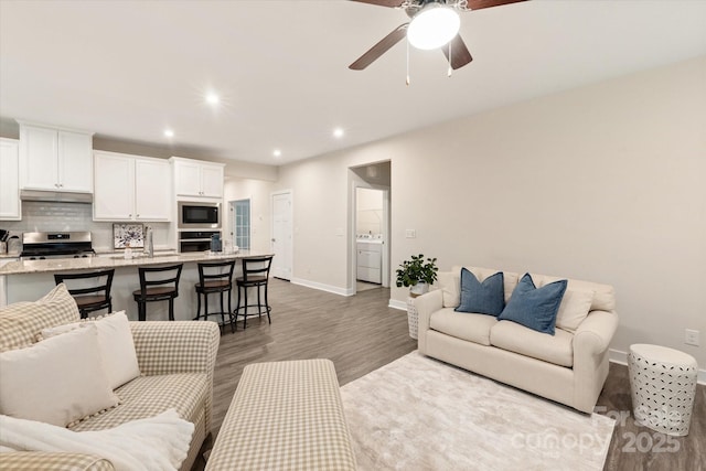 living room featuring a ceiling fan, baseboards, wood finished floors, and recessed lighting