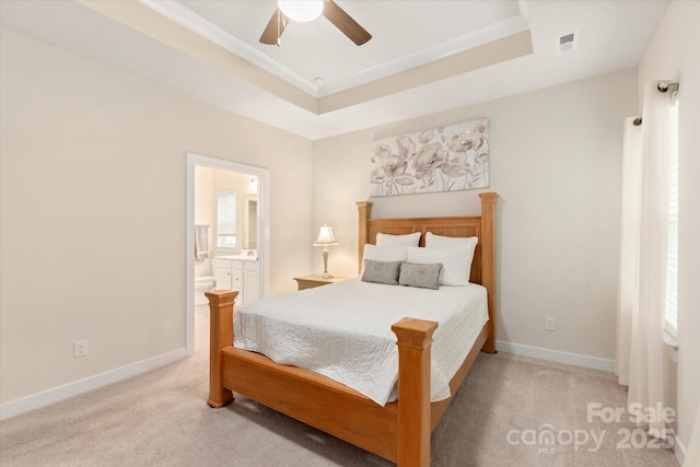 bedroom with a tray ceiling, visible vents, light carpet, and baseboards