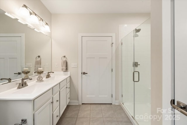 full bathroom featuring a shower stall, double vanity, a sink, and tile patterned floors