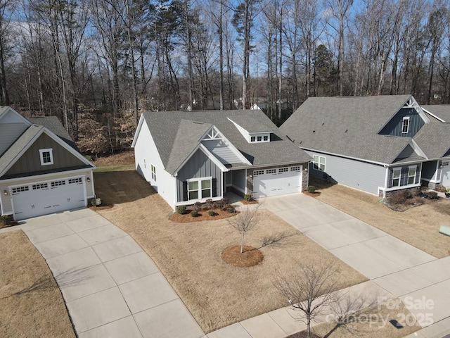 view of front of house with board and batten siding, concrete driveway, a shingled roof, and a garage