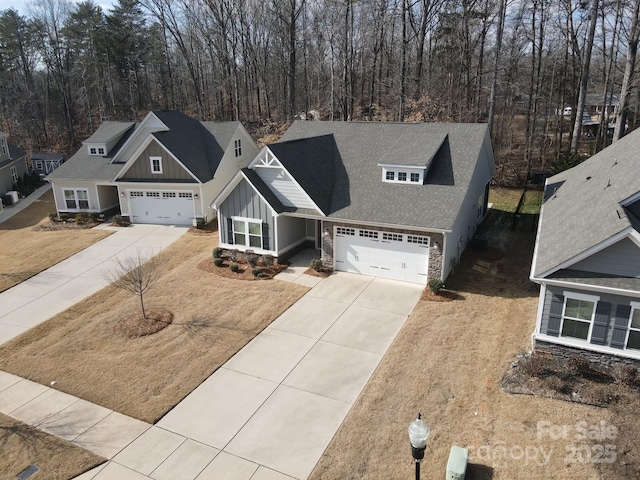 craftsman house with board and batten siding, roof with shingles, driveway, and a garage