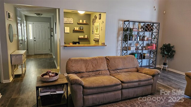 living room featuring a textured ceiling, wood finished floors, and baseboards