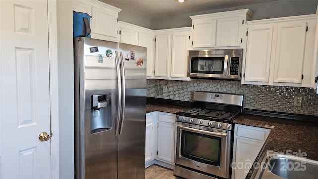 kitchen featuring white cabinets, appliances with stainless steel finishes, decorative backsplash, and a textured ceiling