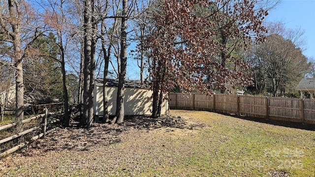 view of yard featuring an outbuilding, a storage shed, and a fenced backyard