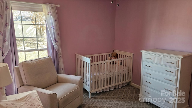 bedroom featuring a crib and baseboards