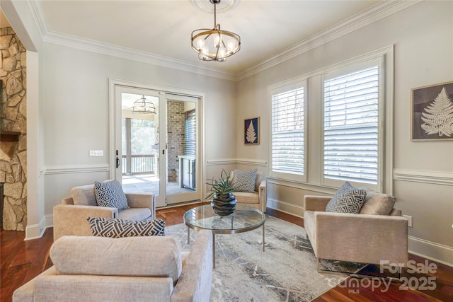 living room featuring a chandelier, a wealth of natural light, a stone fireplace, and dark hardwood / wood-style floors