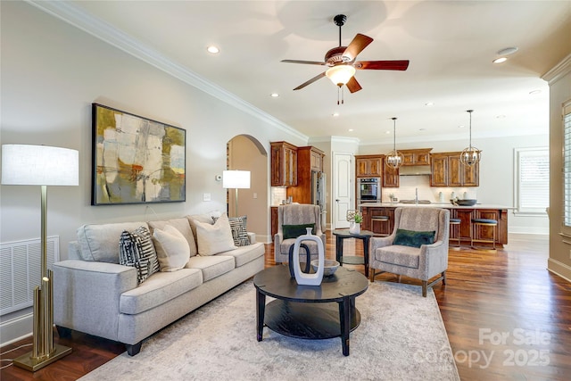 living room featuring ceiling fan, sink, dark hardwood / wood-style floors, and ornamental molding