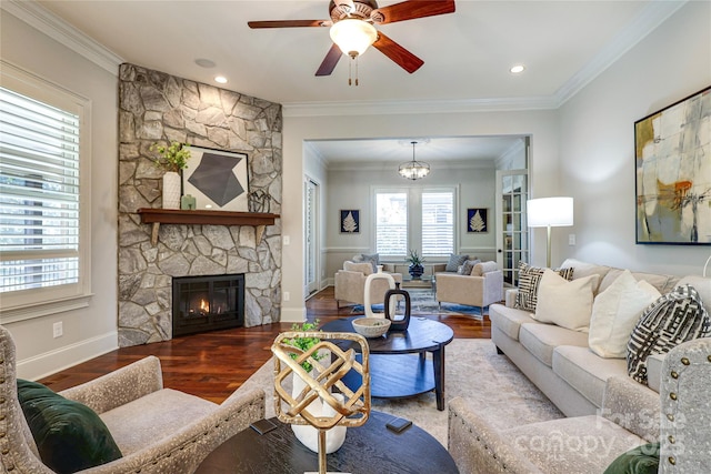 living room featuring hardwood / wood-style flooring, ornamental molding, ceiling fan with notable chandelier, and a fireplace