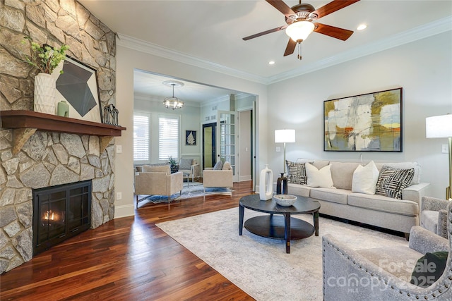 living room with a fireplace, ornamental molding, dark hardwood / wood-style floors, and ceiling fan with notable chandelier