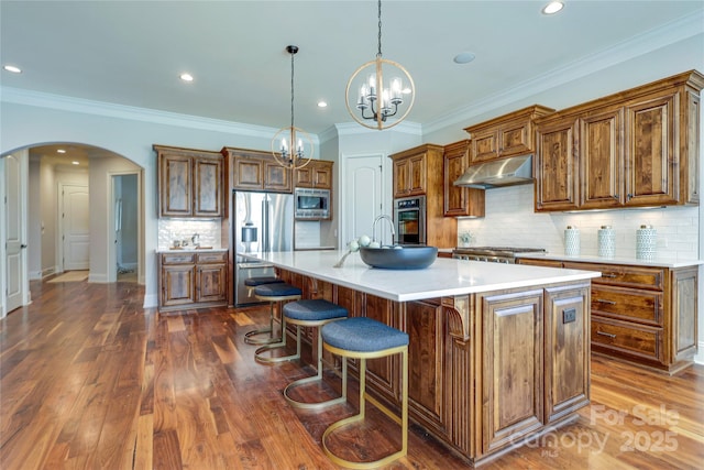 kitchen featuring a breakfast bar, a spacious island, dark wood-type flooring, appliances with stainless steel finishes, and pendant lighting