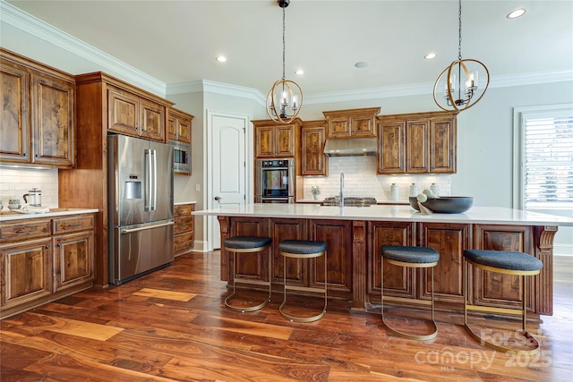 kitchen with a center island with sink, appliances with stainless steel finishes, a chandelier, and decorative light fixtures