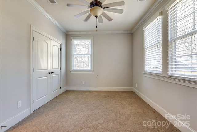 unfurnished bedroom with multiple windows, a closet, crown molding, and light colored carpet