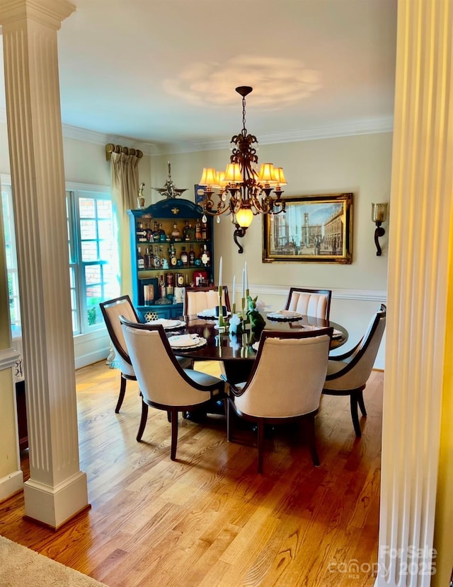 dining area with ornamental molding, wood finished floors, and an inviting chandelier