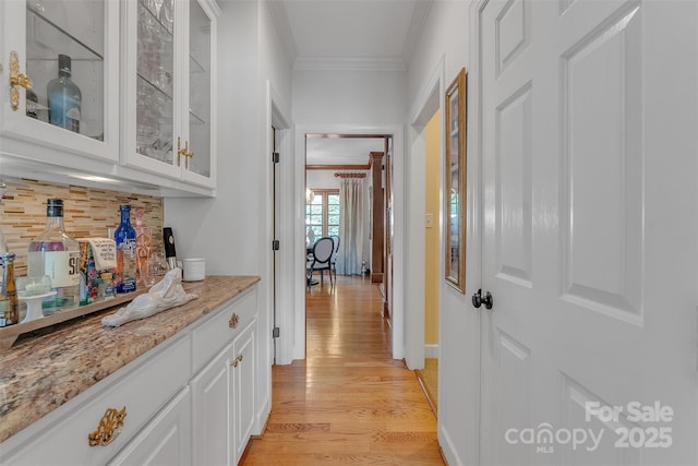 hall featuring baseboards, light wood-style floors, and crown molding