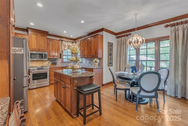 kitchen featuring light stone countertops, a center island, appliances with stainless steel finishes, brown cabinets, and decorative backsplash