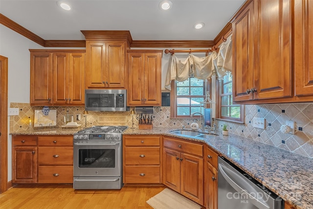 kitchen featuring appliances with stainless steel finishes, brown cabinetry, and a sink