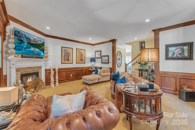 living room featuring light carpet, a wainscoted wall, a premium fireplace, stairs, and crown molding