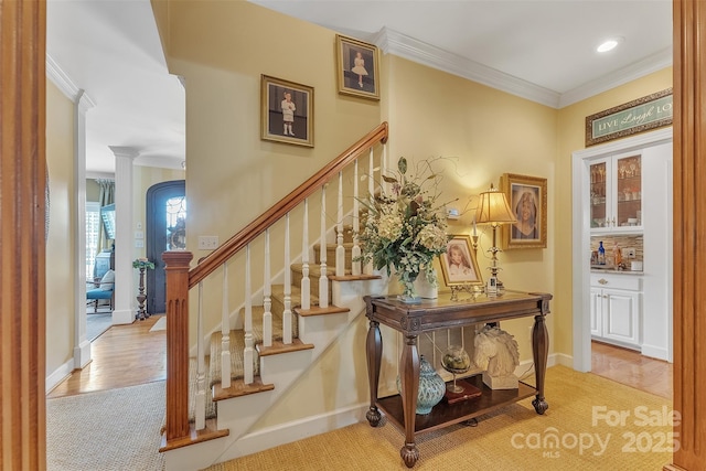 staircase featuring baseboards, arched walkways, wood finished floors, crown molding, and recessed lighting