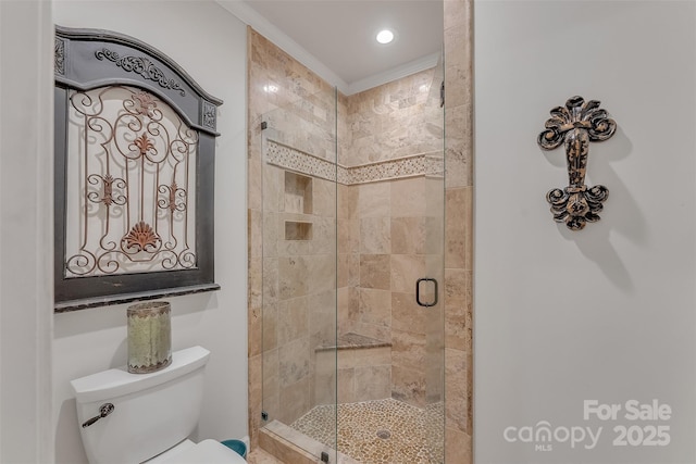 bathroom featuring toilet, a stall shower, and crown molding