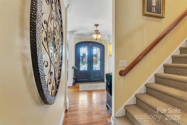 entrance foyer with french doors, crown molding, stairway, light wood-style flooring, and baseboards