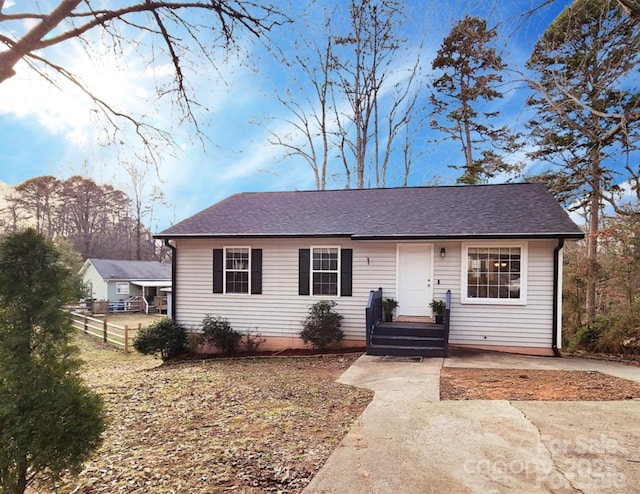 ranch-style house with fence and roof with shingles